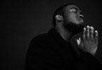 black man praying with eyes closed