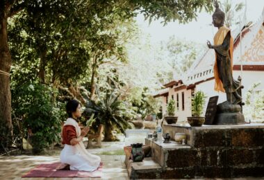 a woman kneeling near a buddha statue