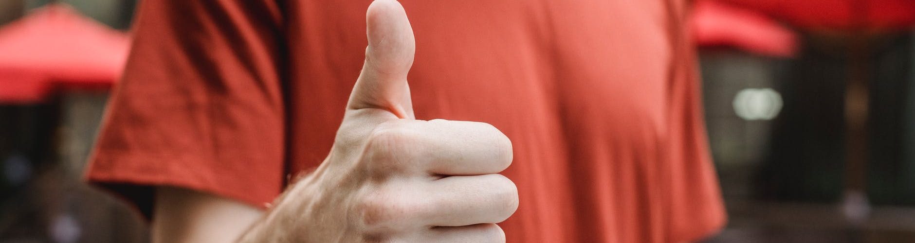 unrecognizable man showing thumb up on city street