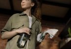 woman in green button up shirt holding clear glass bottle