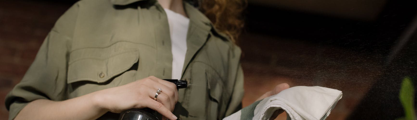 woman in green button up shirt holding clear glass bottle