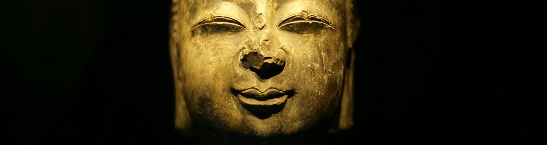old golden sculpture of buddha against black background