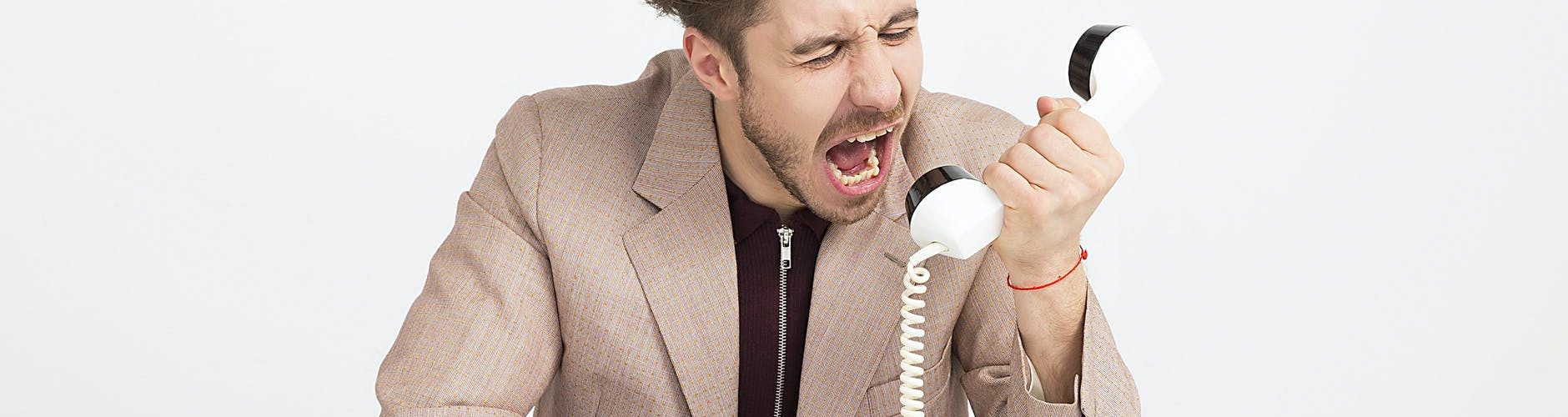 man wearing brown suit jacket mocking on white telephone