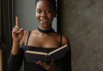 black woman standing in room and reading book