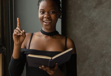 black woman standing in room and reading book