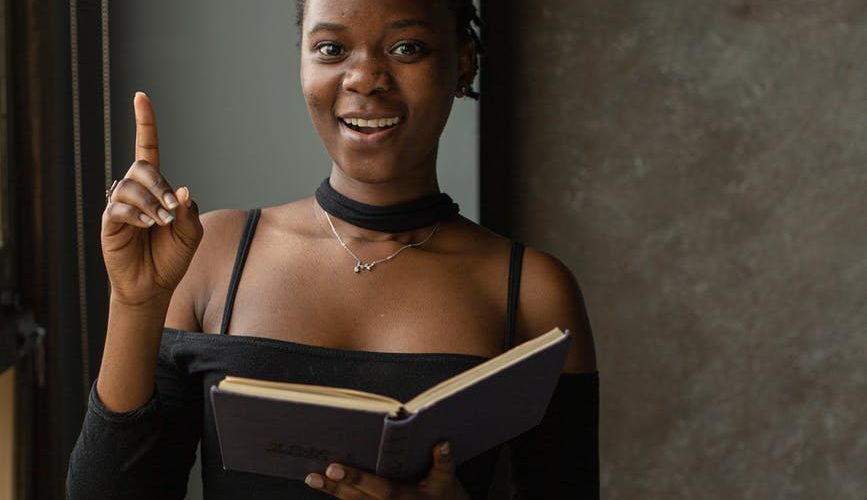 black woman standing in room and reading book
