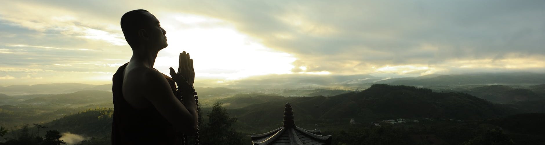 monk holding prayer beads across mountain