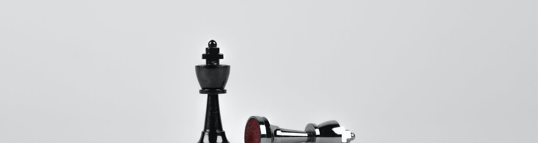 two silver chess pieces on white surface