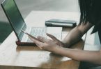 woman sitting on chair beside table while using phone
