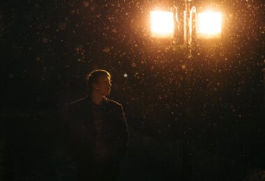man in black jacket standing near a lamp post
