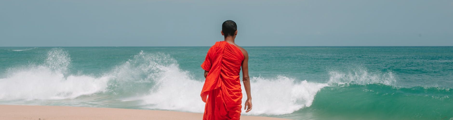 unrecognizable young ethnic man walking on seashore