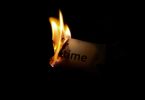 person holding burning paper in dark room