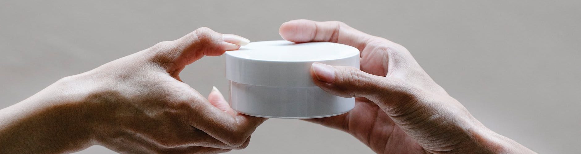 crop woman passing jar of cream to girlfriend