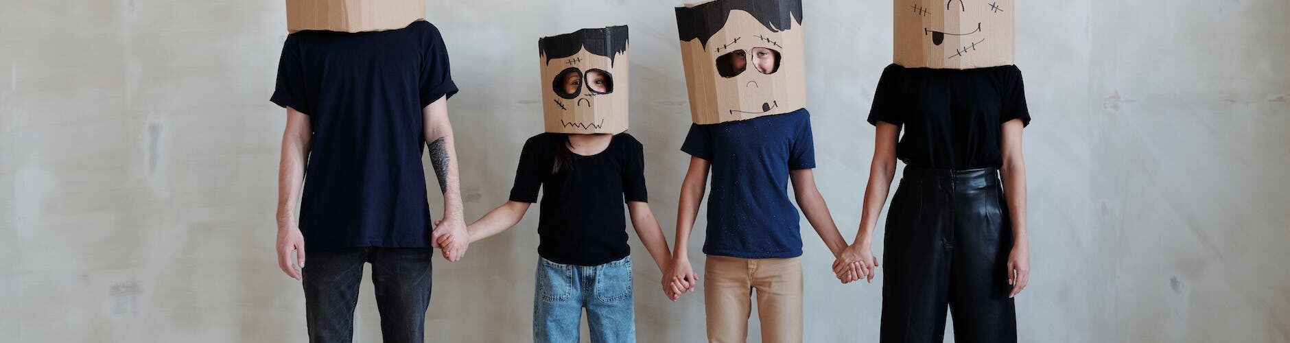 a family wearing diy cardboard box mask while holding each other s hands