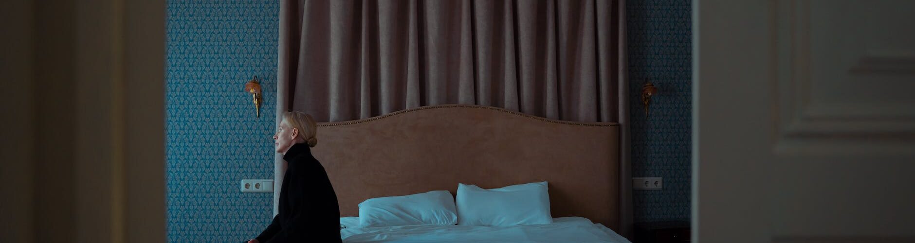 a woman sitting alone on her bed