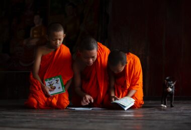 young buddhist monks studying books on the floor