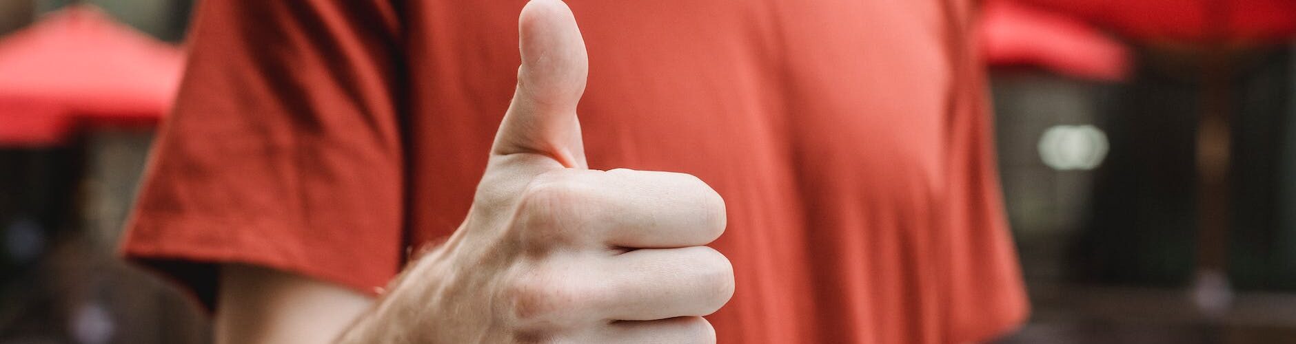 unrecognizable man showing thumb up on city street