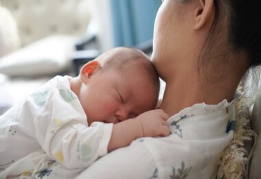 woman lying and holding a newborn baby on her chest
