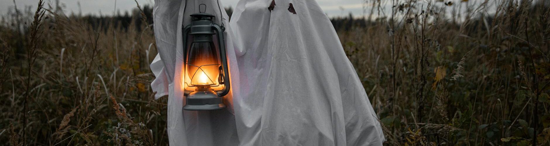 personin ghost costume holding a lantern