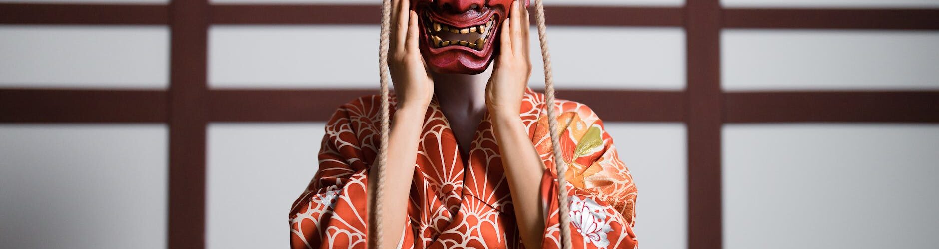 a person in a kimono wearing a hannya mask