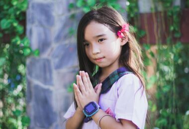 girl in purple short sleeve shirt with green and black plaid collar wearing black digital watch