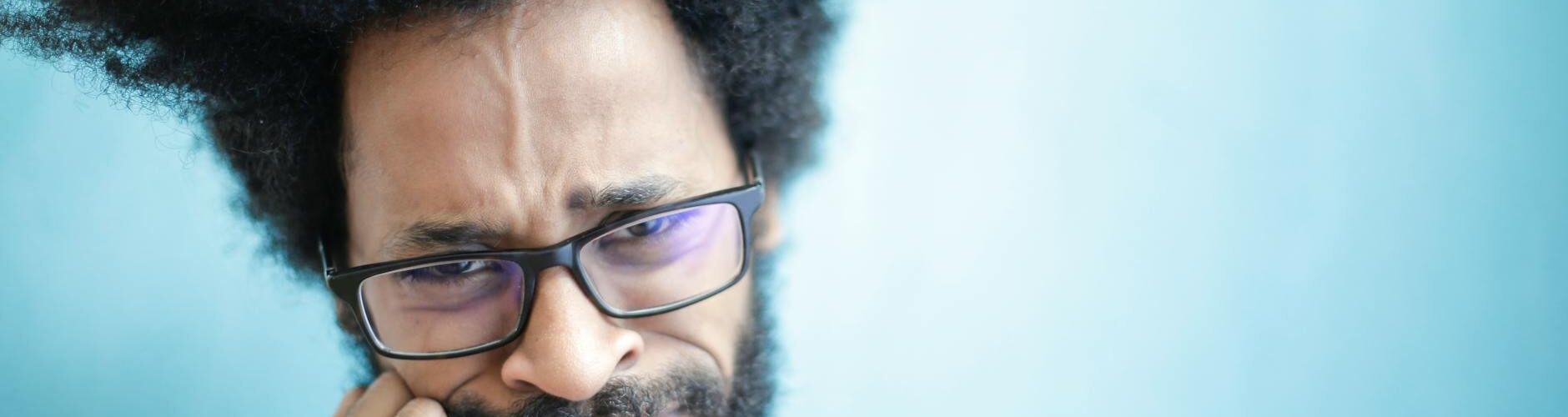 frustrated ethnic man in casual wear on blue background in studio