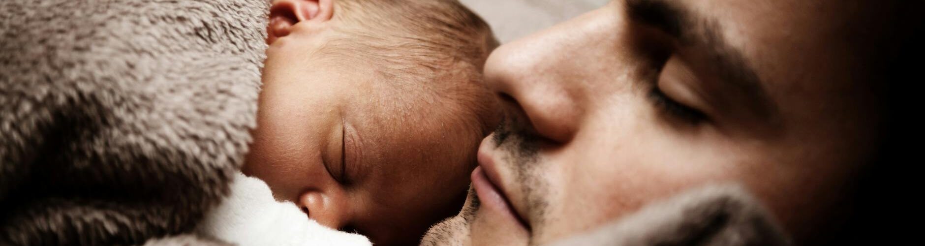 close up of a dad and his little baby sleeping together
