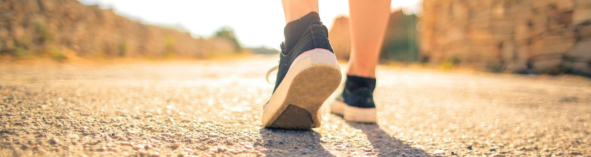 woman walking on pathway under the sun