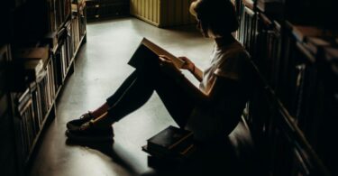 woman sitting on floor reading book