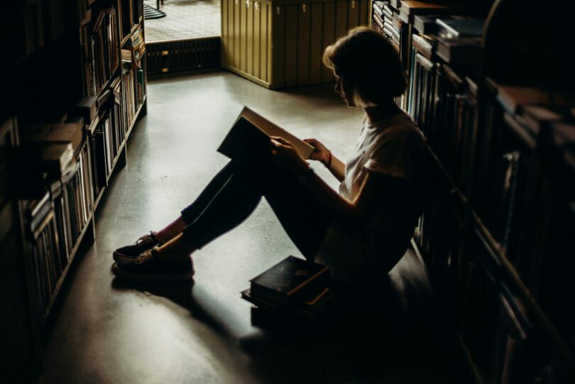 woman sitting on floor reading book